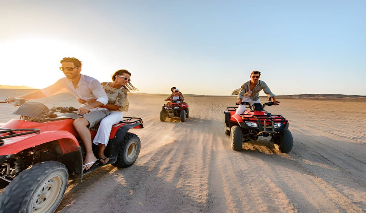 happy friends driving a quad bike in the desert in Dubai